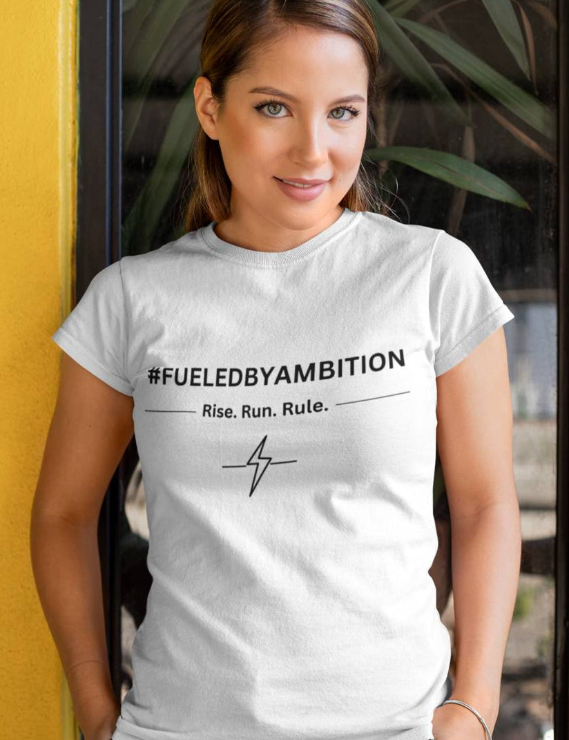 Woman wearing a white t-shirt with '#FUELEDBYAMBITION' text, standing against a yellow wall.